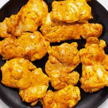 Baked boneless skinless chicken thighs on a plate.