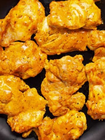 Baked boneless skinless chicken thighs on a plate.