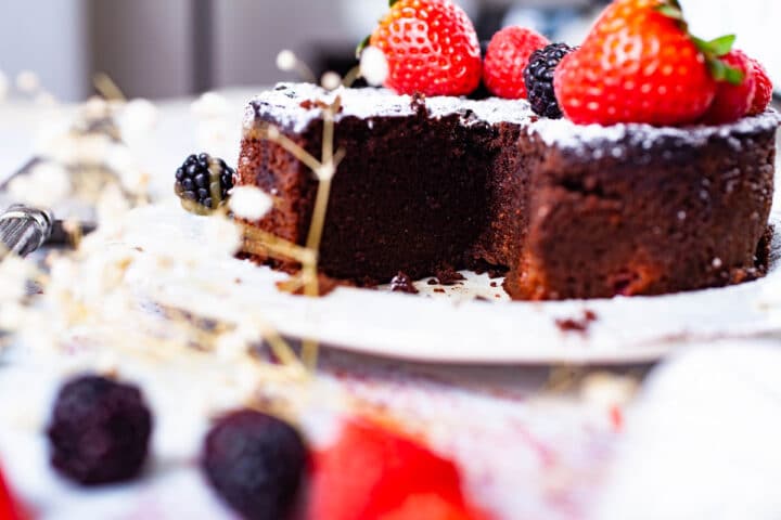 A close up of a Keto chocolate cake with a piece already cut ou.