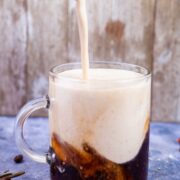 Frothy milk concoction being poured into a cold brew coffee to make a latte.