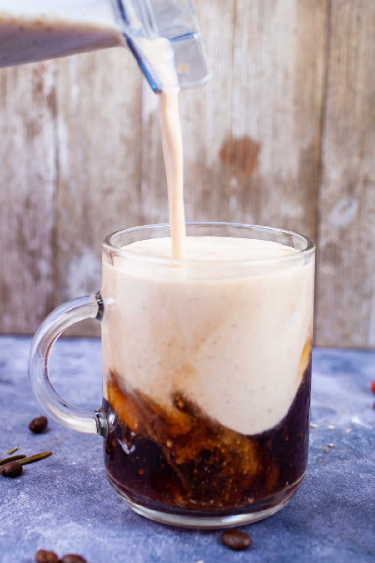 Frothy milk concoction being poured into a cold brew coffee to make a latte.