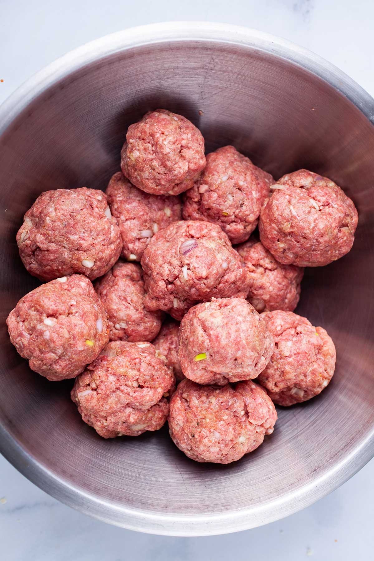 Raw meatballs in a stainless steel bowl.