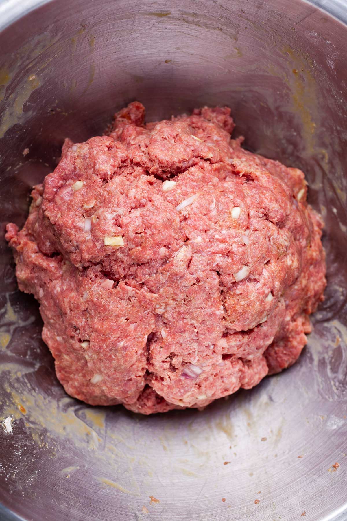 Prepared raw ground bison meat in a stainless steel bowl.