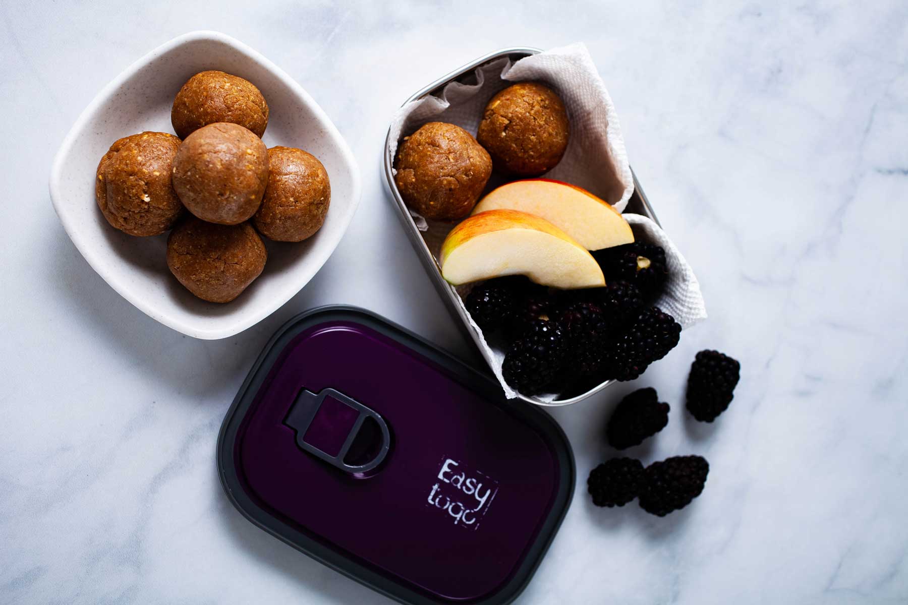 Bliss balls and fruits in a snack container.