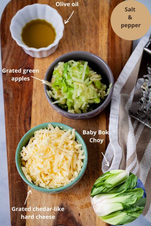 Ingredients such as olive oil, grated green apples, baby bok choy, grated Chedar-like cheese, and salt and pepper to make a roasted baby bok choy recipe.