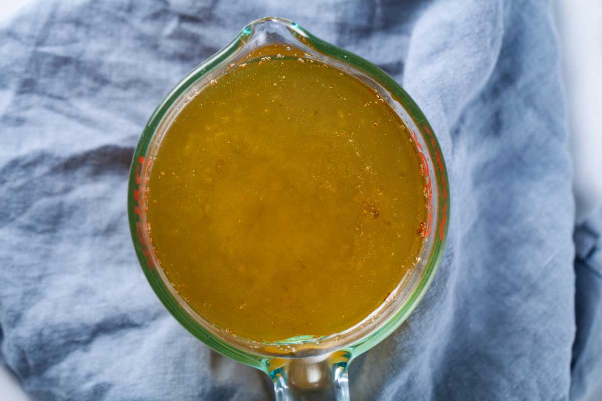 A measuring cup filled with bone broth soup.