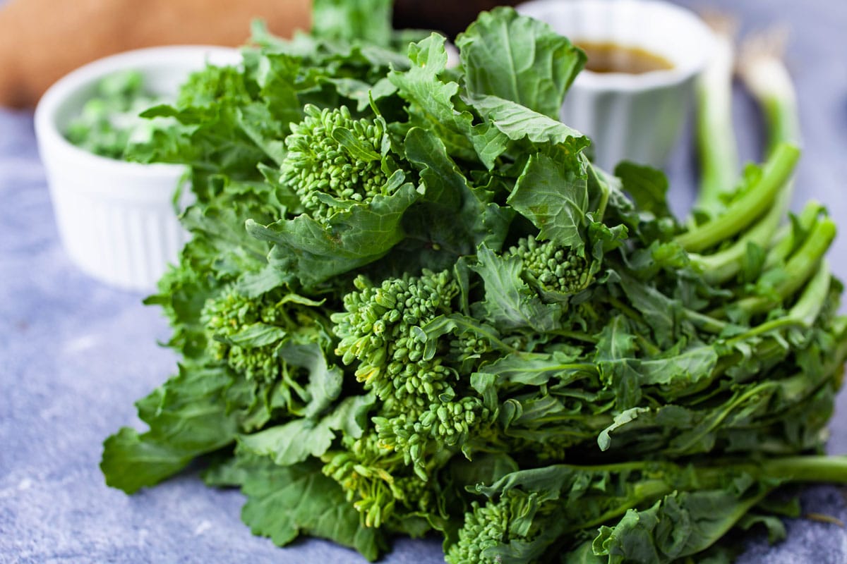 A bushel of broccoli rabe resting on a table.