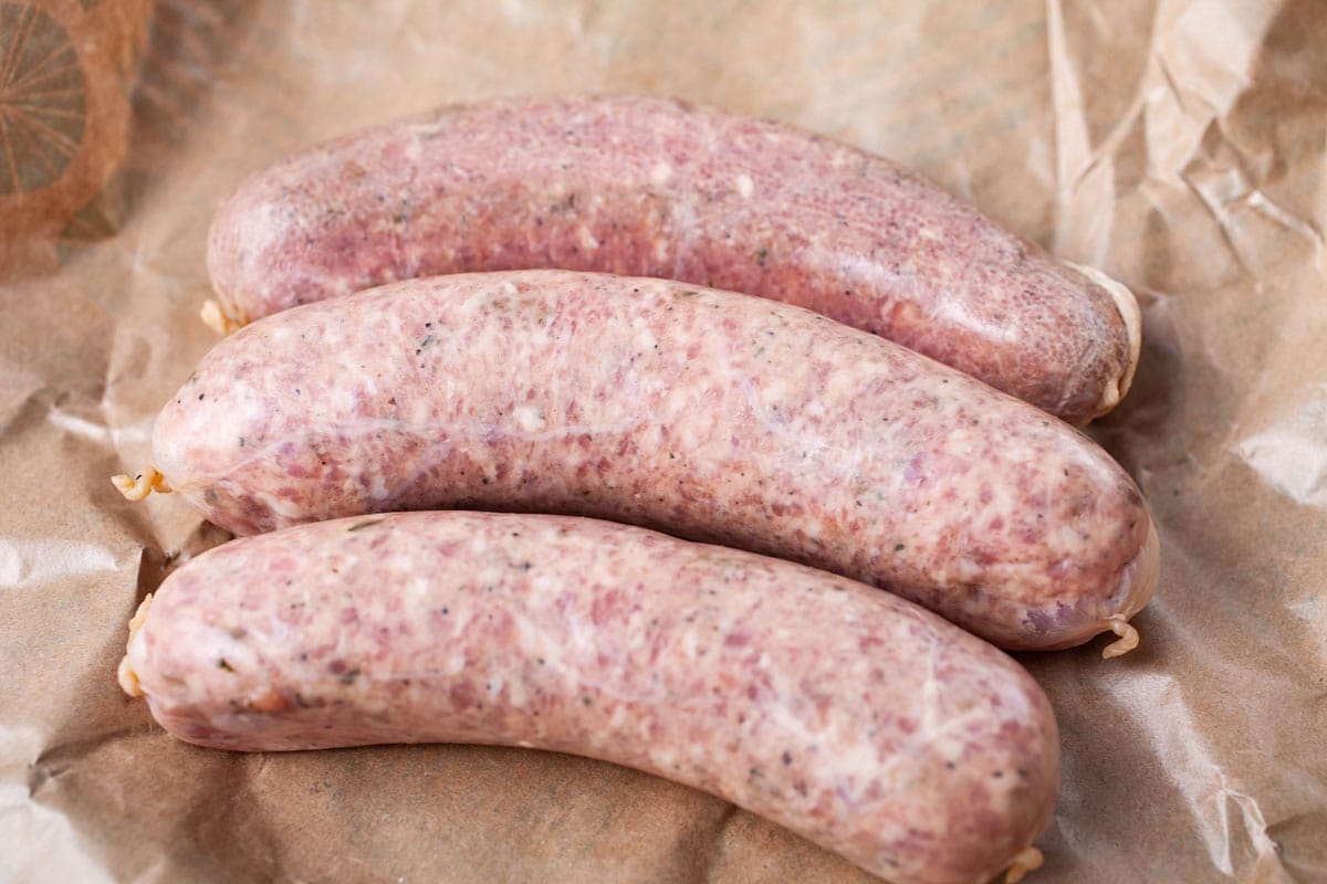 Three raw sausages resting on brown butcher paper.