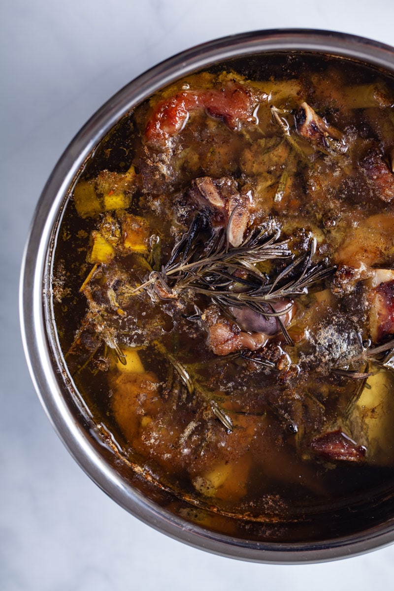 A pot filled with cooked bone broth and meat bones.