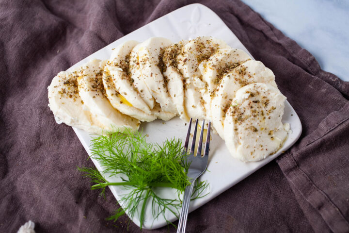 A small plate with fresh mozzarella slices, topped with oregano.