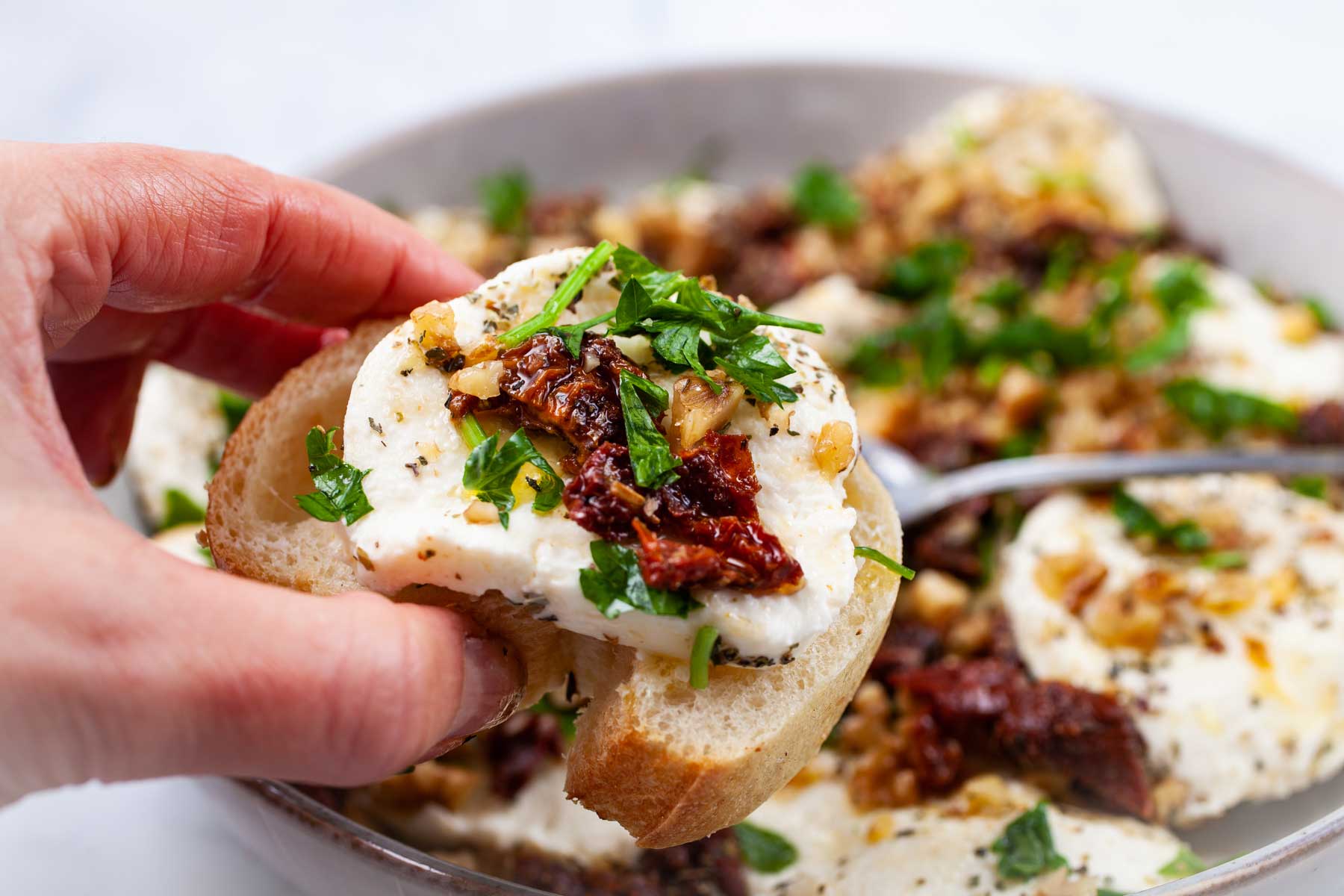 A hand holding a mozzarella bruschetta in a hand.