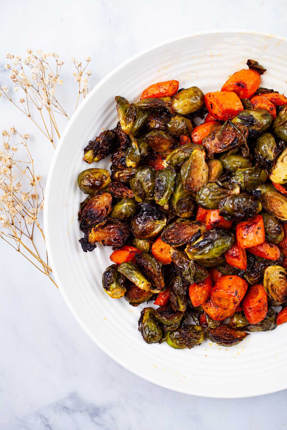 Crispy roasted Brussels Sprouts and carrots on a serving plate.