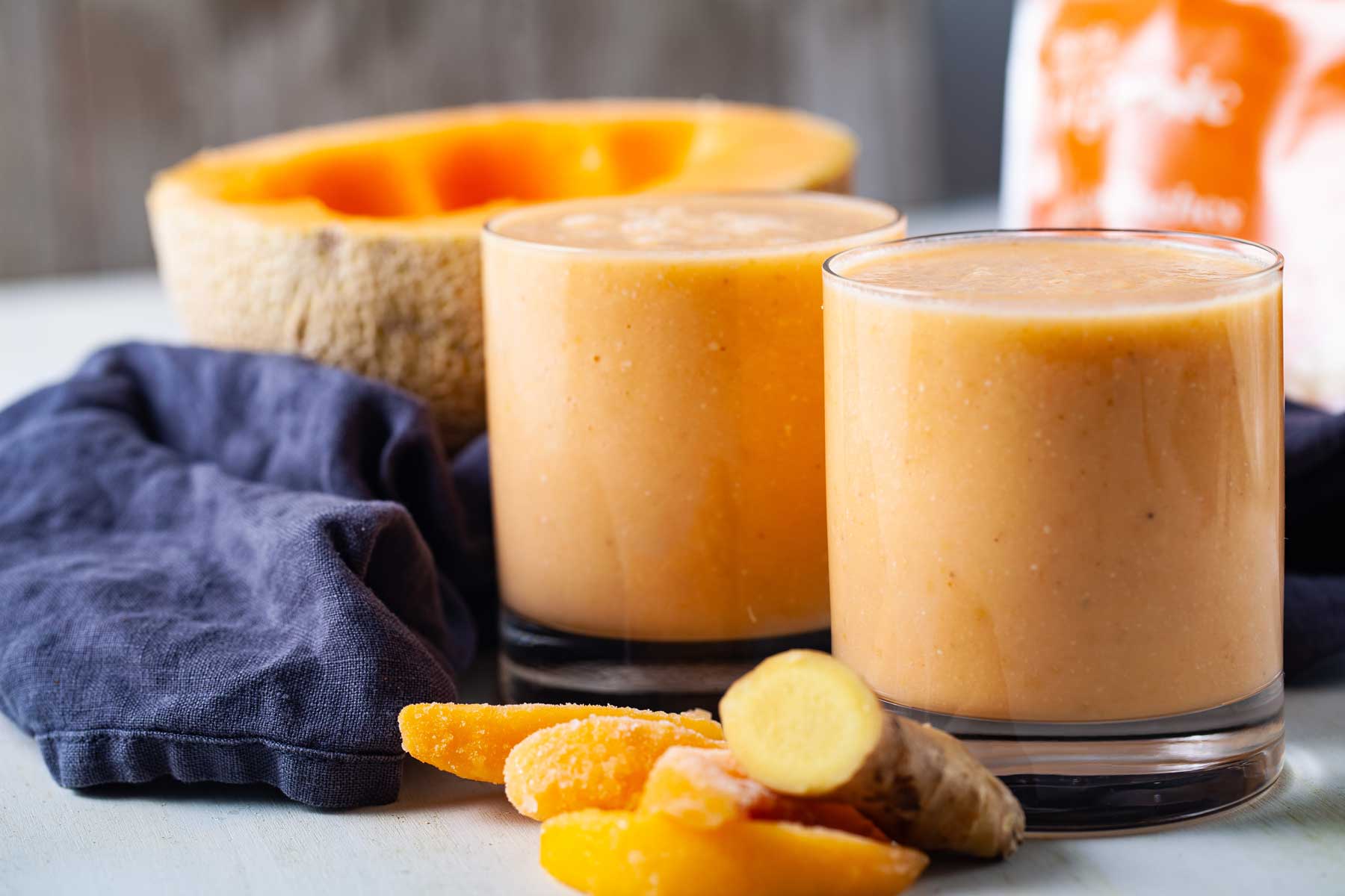 Two glasses filled with creamy cantaloupe smoothie drink.