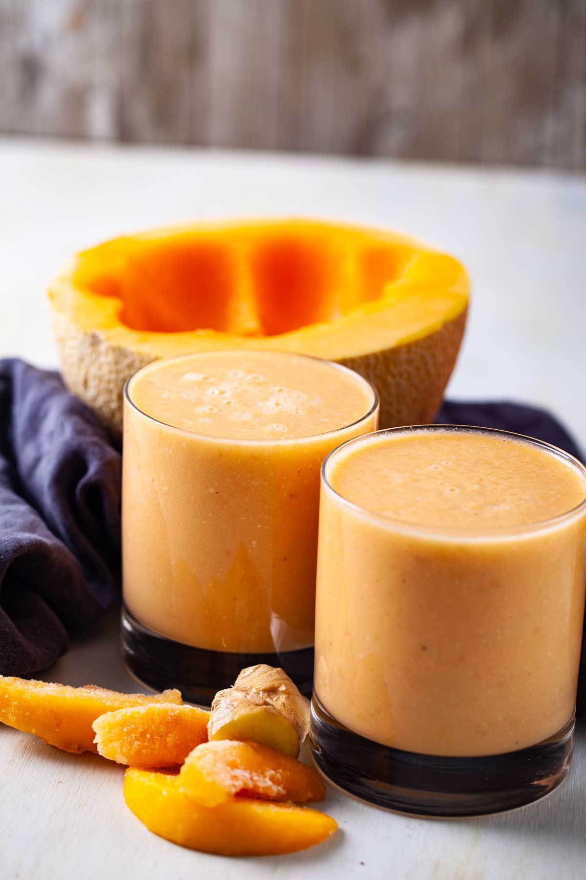 Two glasses filled with creamy cantaloupe smoothie drink.