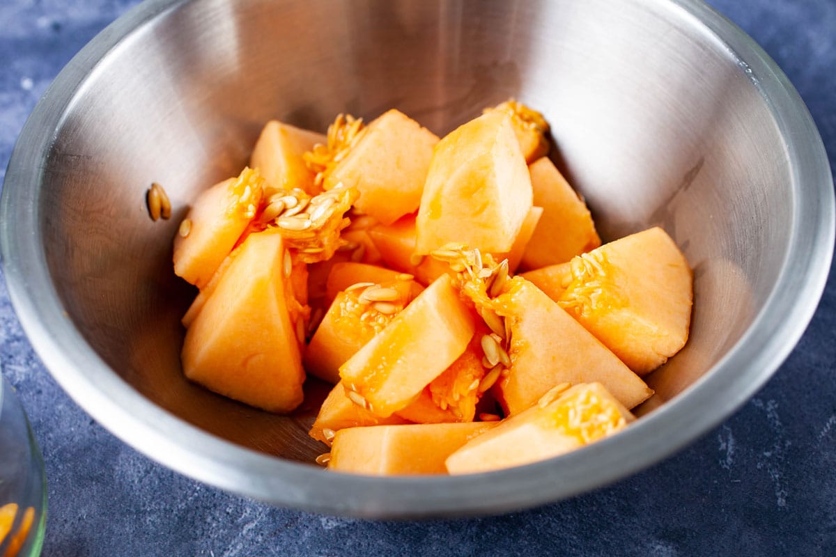 A stainless steel bowl filled with fresh pieces of cantaloupe.