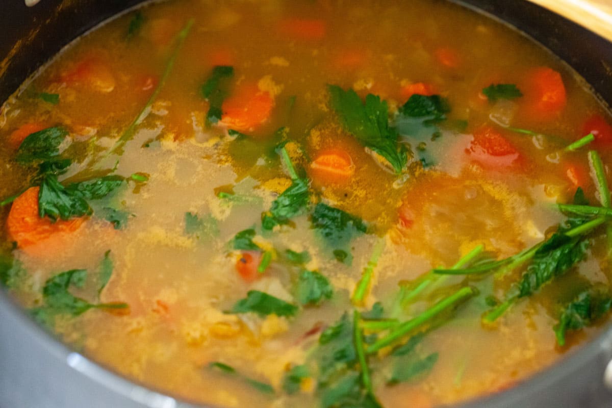 A large pot with broth and vegetables.