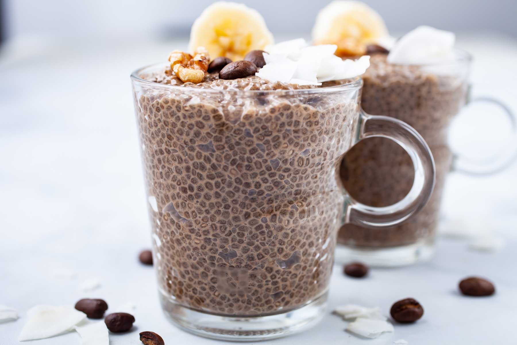 Coffee chia seed pudding in mini cups, topped with walnuts, chopped banana, and coconut flakes.