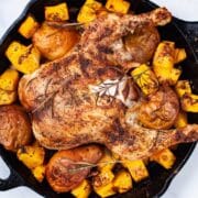 Whole roasted chicken leg, squash and pears in a cast-iron skillet.