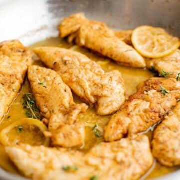 Chicken tenders in garlic butter in a skillet.