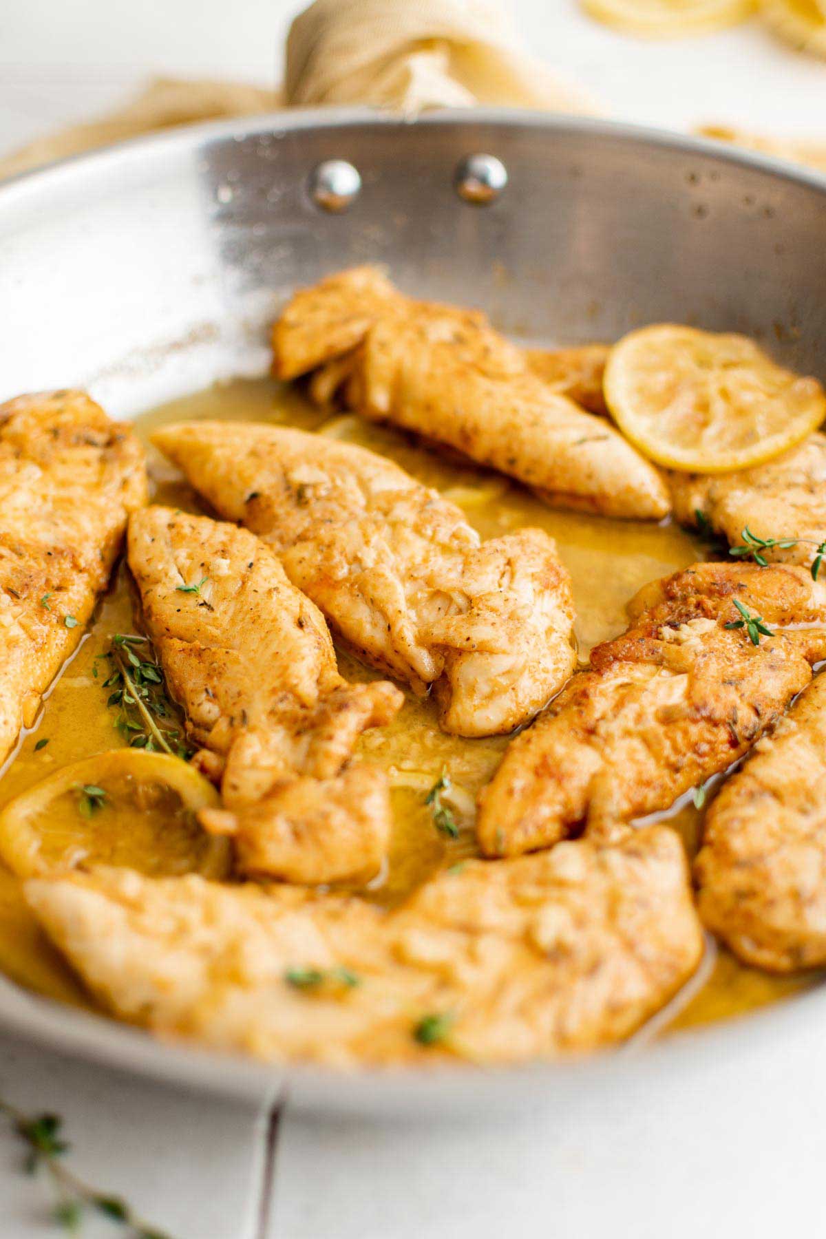 Chicken tenders in garlic butter in a skillet.