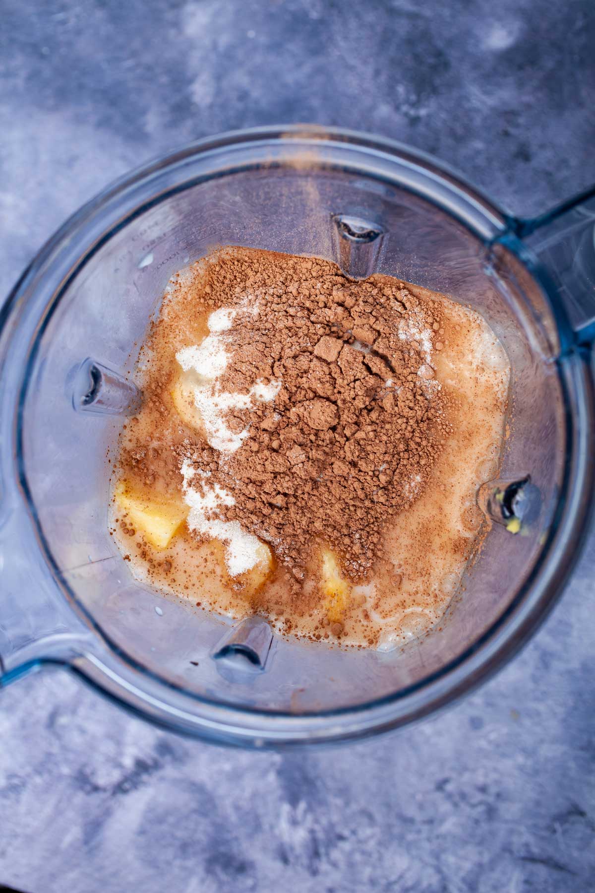 Almond milk, pineapple, collagen powder, and cacao powder in a blender.