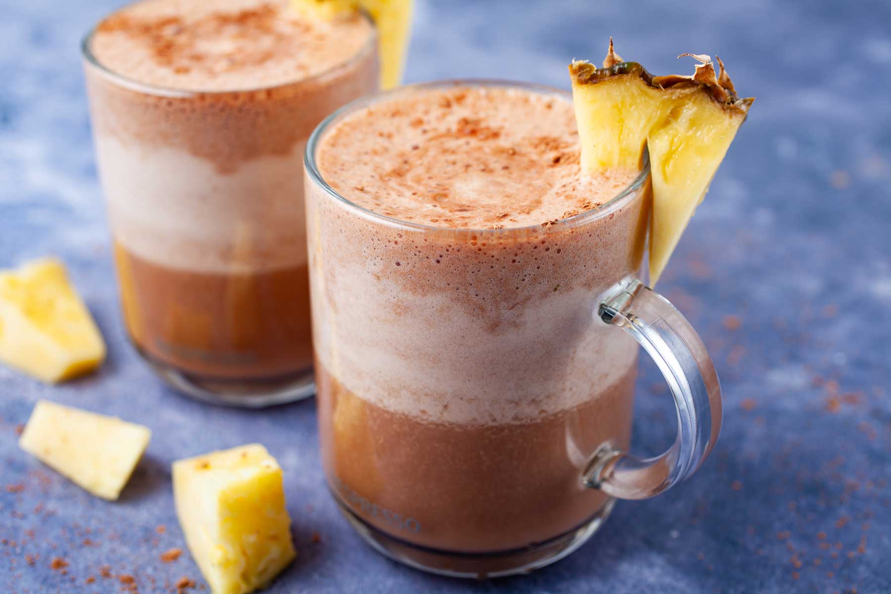 Frothy and chocolaty smoothie drinks topped with fresh pineapple slices.