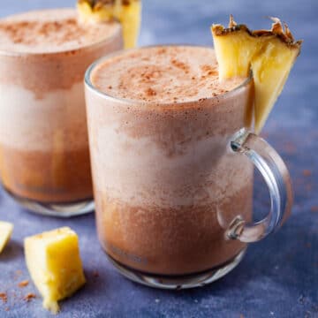 Frothy and chocolaty smoothie drinks topped with fresh pineapple slices.