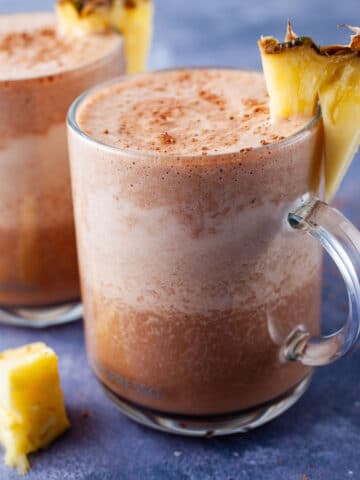 Frothy and chocolaty smoothie drinks topped with fresh pineapple slices.