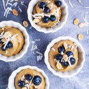 Small cups filled with vegan avocado mousse and topped with berries and coconut shreds.