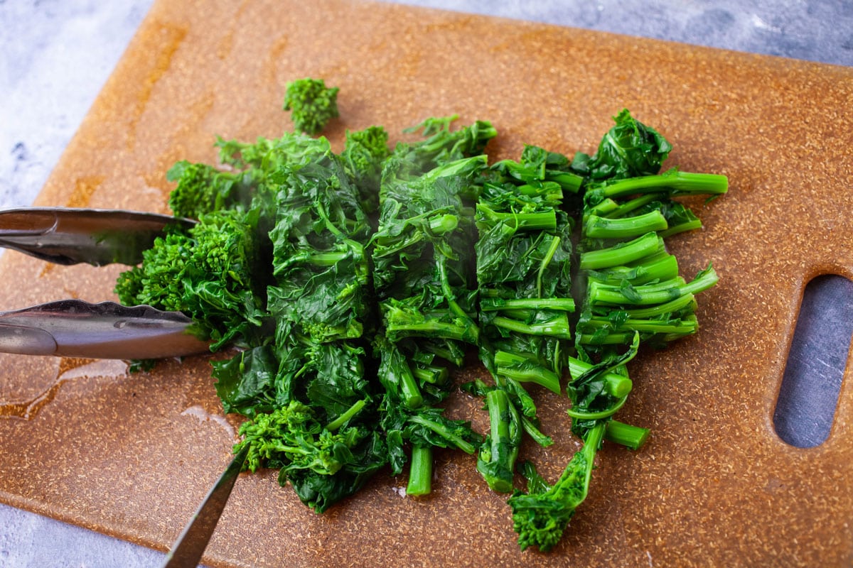 Chopped cooked broccoli rabe resting on a cutting board.