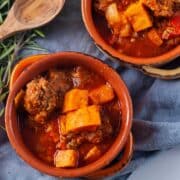 Two terracotta bowls filled with a meat sweet potato and stew.