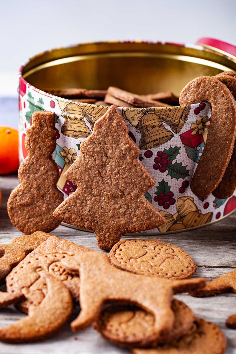 Speculoos cookies in different shapes laid out in front of a cookie box.