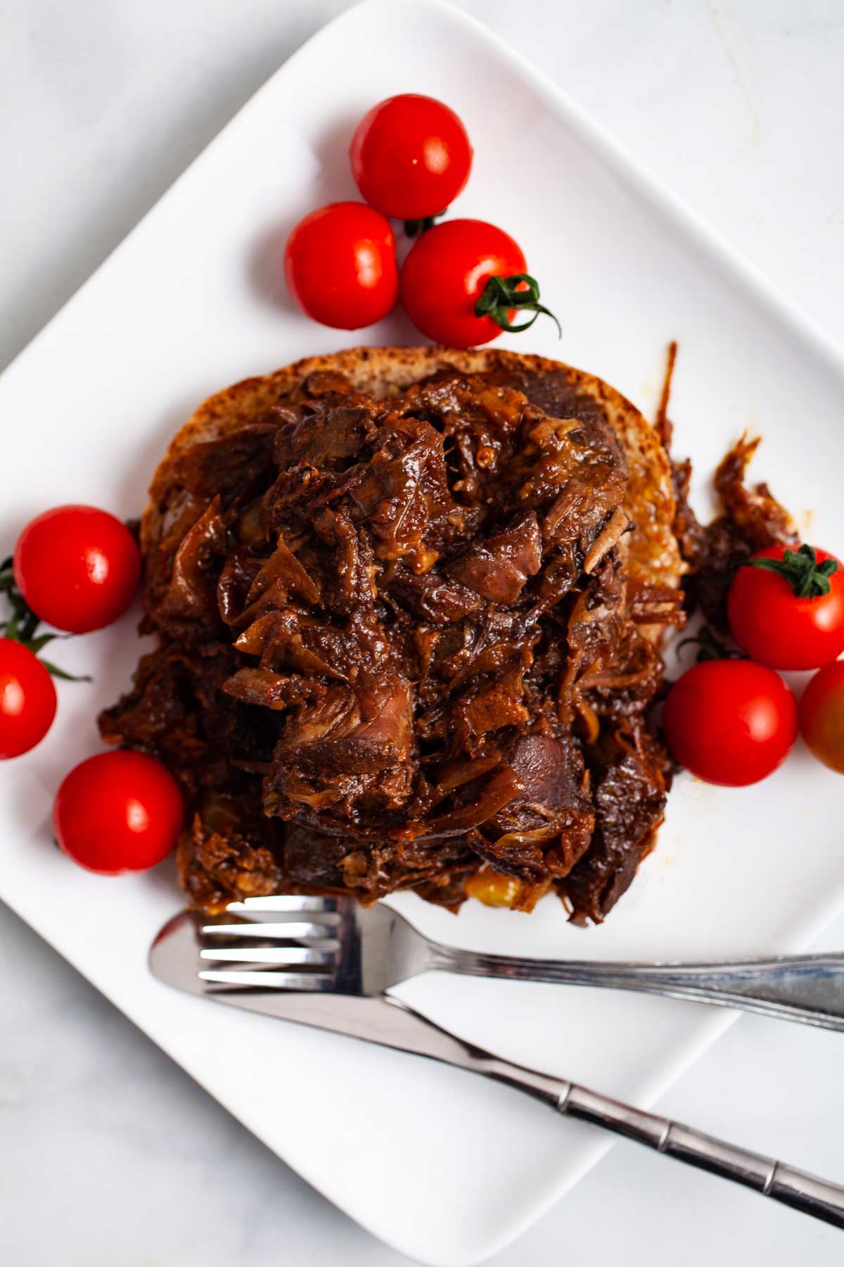 Leftover pot roast on a sandwich served with tomatoes.