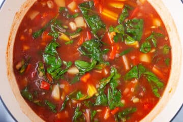 Homemade vegetable soup in a Dutch pan with rainbow chard and lima beans.