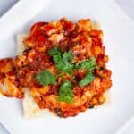 An open Focaccia Sandwich with pan-fried cod fish in red tomato sauce.