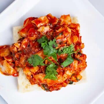 An open Focaccia Sandwich with pan-fried cod fish in red tomato sauce.