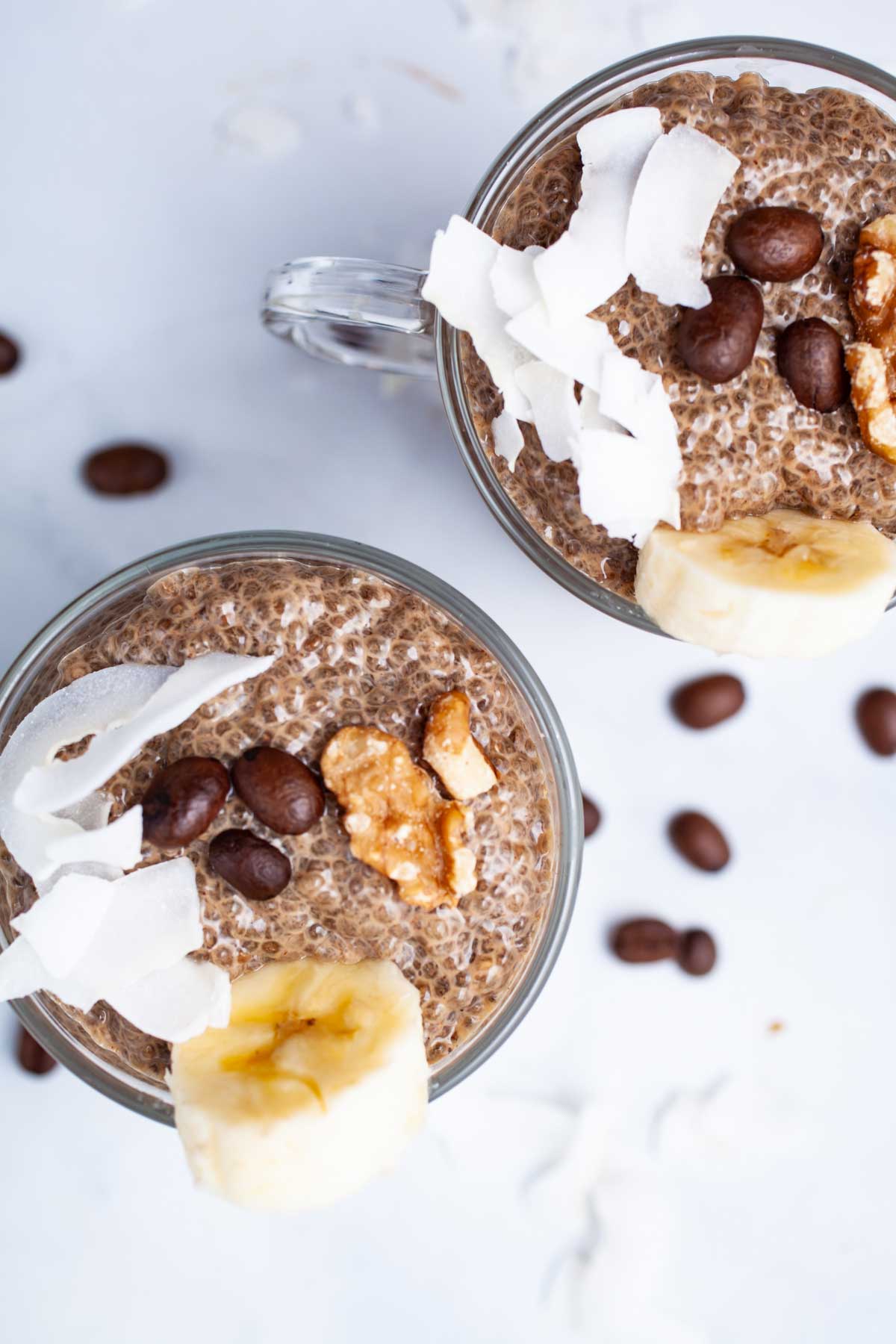 Coffee chia seed pudding in mini cups, topped with walnuts, chopped banana, and coconut flakes.