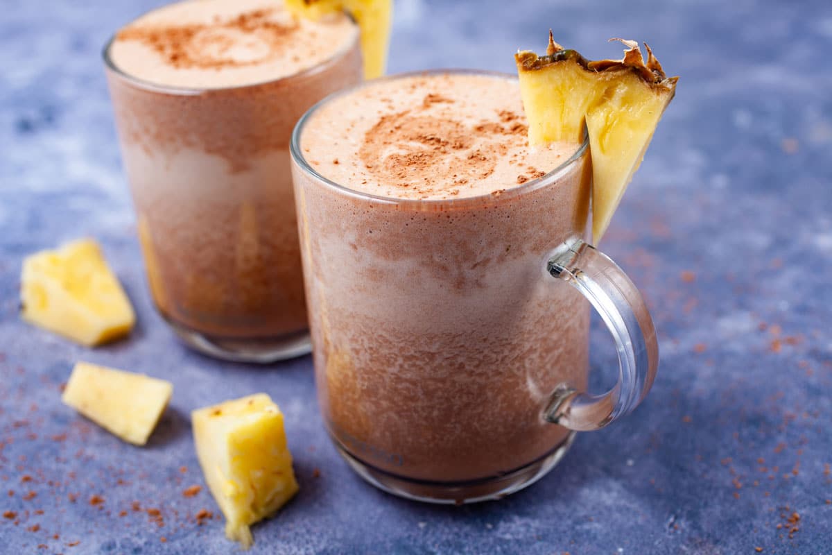 Frothy and chocolaty smoothie drinks topped with fresh pineapple slices.