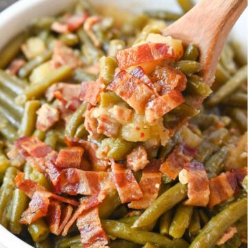 Cooked green beans topped with bacon bits served in a bowl.