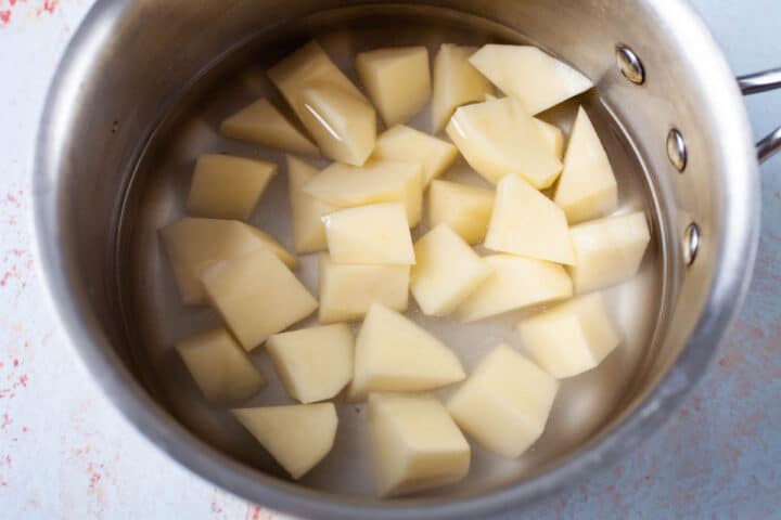A small saucepan filled with cut potatoes in water.