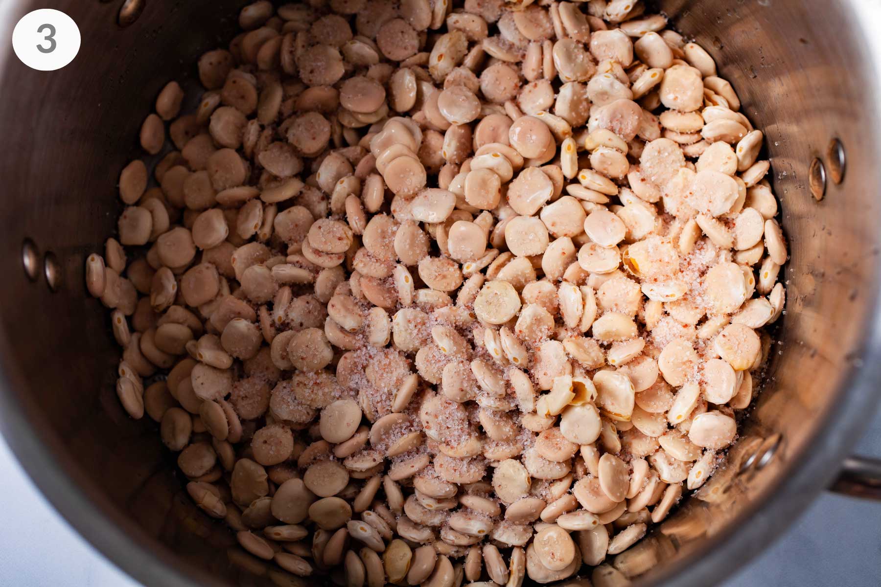 A large pot filled with uncooked Lupini beans topped with salt.