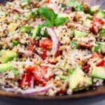 Cucumber quinoa salad with a creamy dressing tossed in. a wooden bowl.