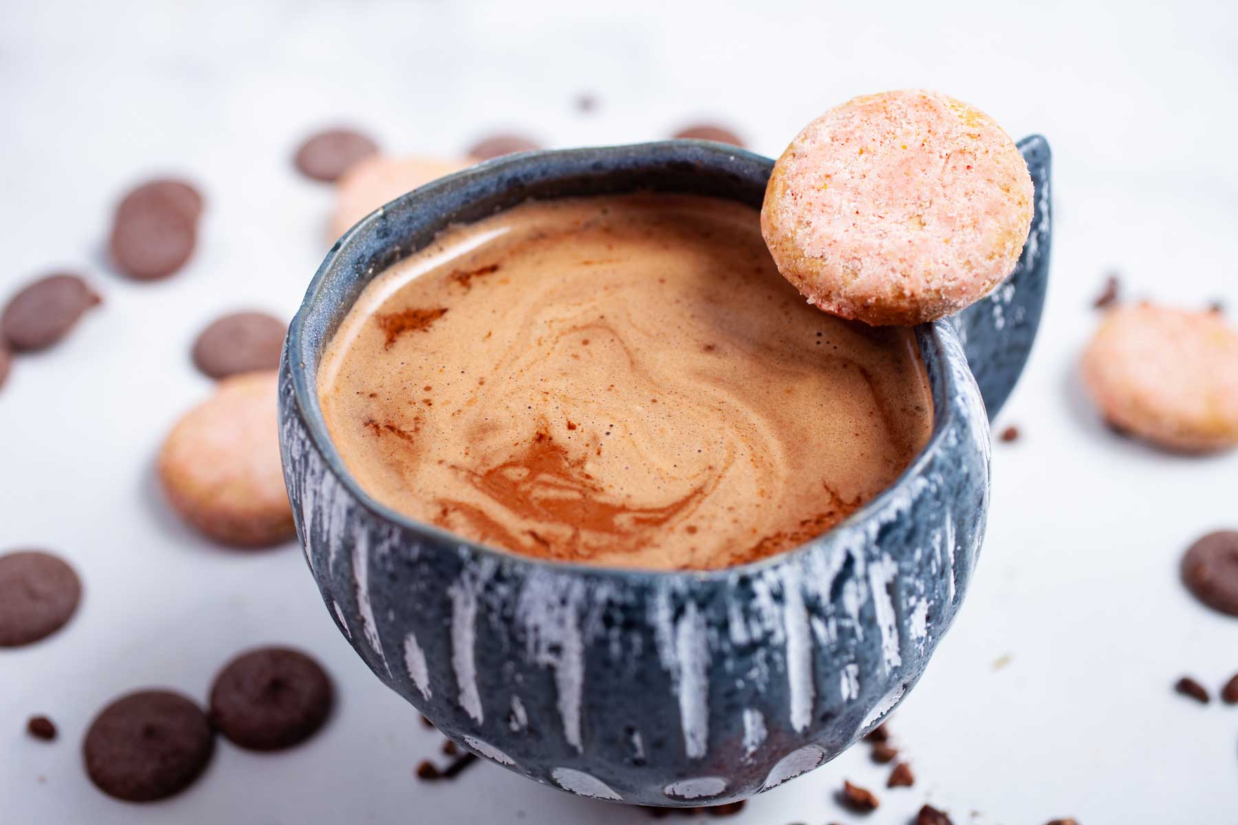 Bone broth hot cocoa in a cup surrounded by cookies and chocolate wafers.
