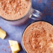 Creamy and frothy chocolate and pineapple smoothies topped with fresh pineapple slices.