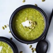 Avocado leek soup served in small bowls topped with seeds and coconut cream.