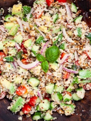 Cucumber quinoa salad with a creamy dressing tossed in. a wooden bowl.