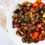 Crispy roasted Brussels Sprouts and carrots on a serving plate.