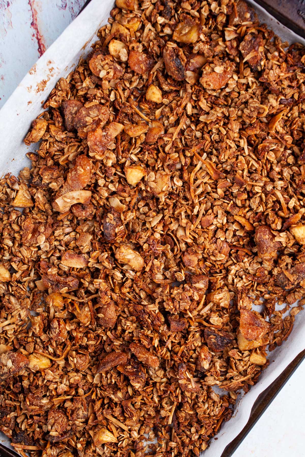 A golden brown baked and crunchy granola in a large baking pan.