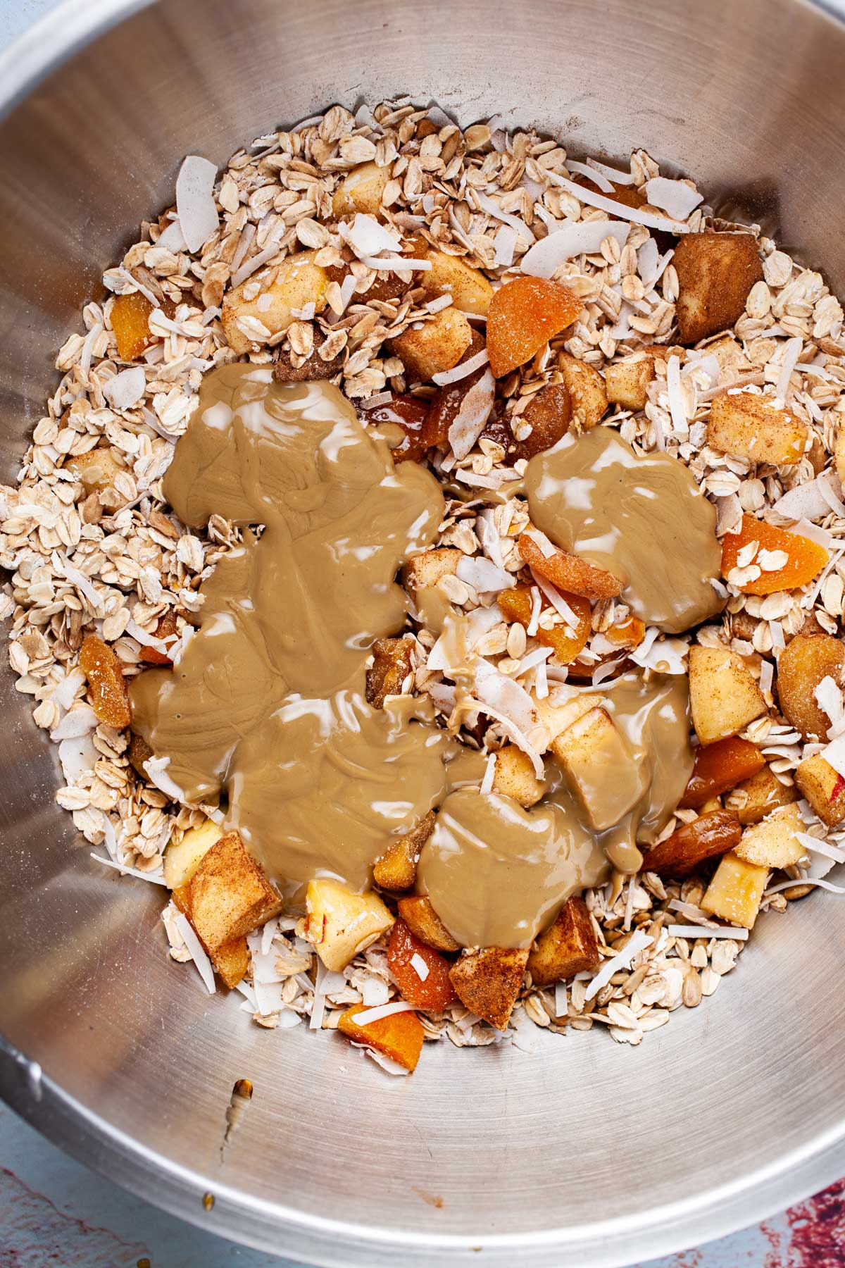 Sunflower seed butter added to an oat mixture in a large mixing bowl.