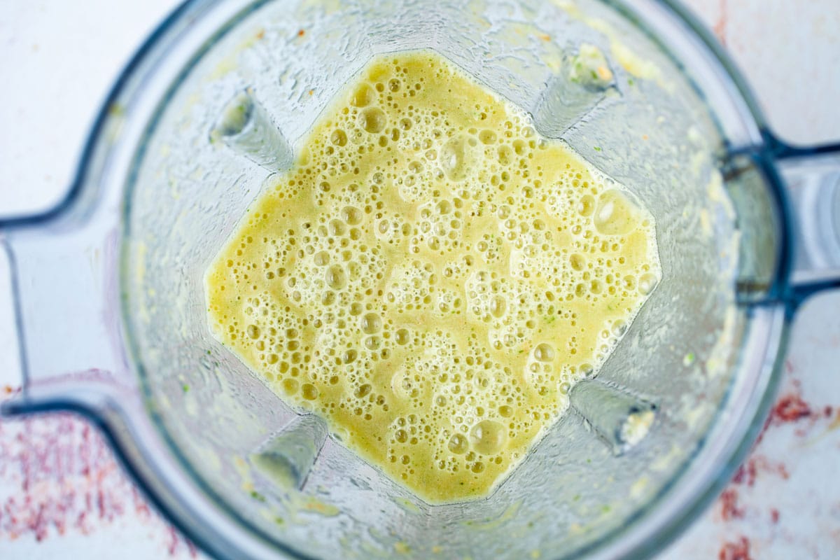 A green yellowish smoothie in a blender.